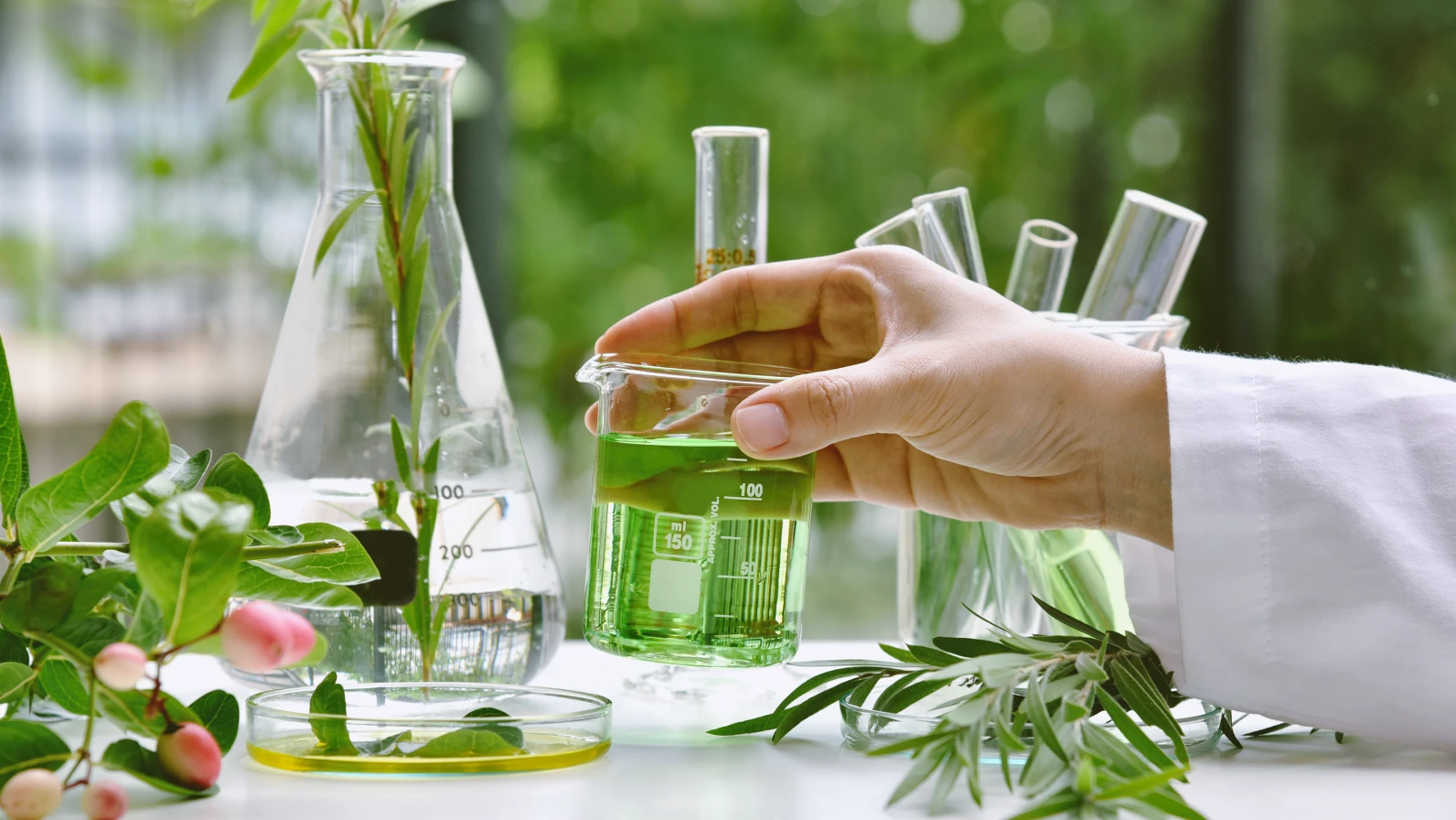 녹색 액체가 담긴 유리잔을 들고 있는 연구원